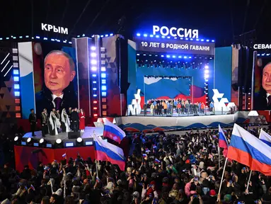 Presiden Rusia dan kandidat presiden Vladimir Putin berpidato di hadapan pendukungnya dalam sebuah acara untuk memperingati 10 tahun aneksasi Rusia atas Krimea di Lapangan Merah, Moskow, 18 Maret 2024. (NATALIA KOLESNIKOVA/AFP)