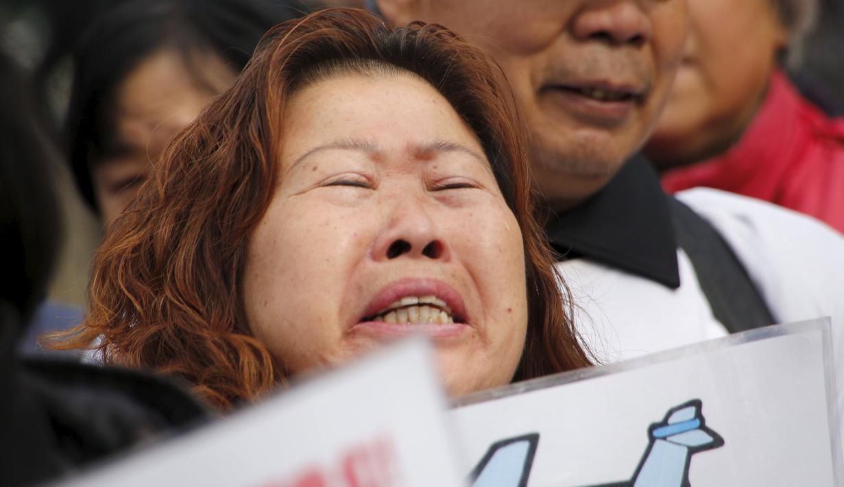 Keluarga penumpang pesawat Malaysia Airlines MH370 berunjuk rasa membawa poster di Lama Temple, Beijing, Cina, (8/3). Poster Tersebut bertuliskan "Ibu akan selalu menunggu. Tidak akan menyerah." (REUTERS/Kim Kyung-hoon)