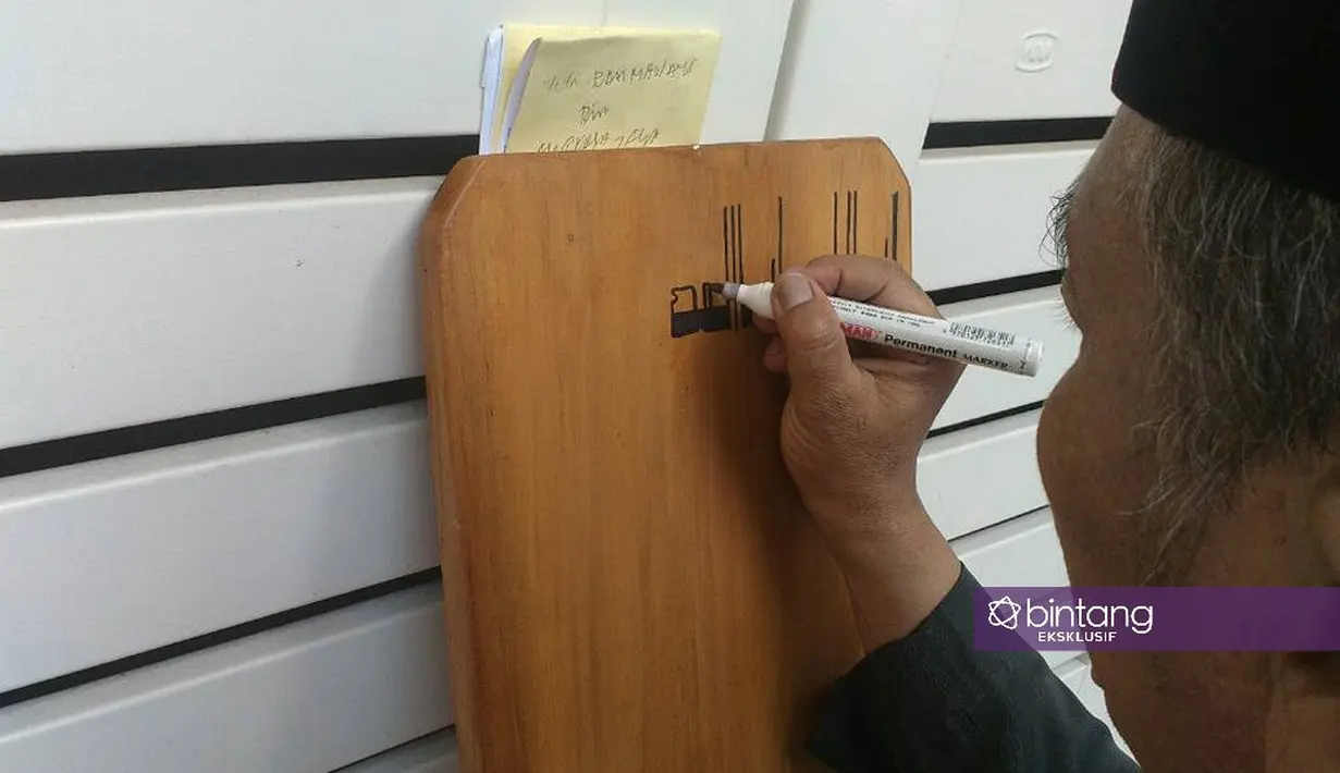 Setiap orang yang hadir di kediaman Jupe sibuk melakukan banyak hal. Tampak di salah satu sudut seorang bapak yang sedang mengukir nama Yuli Rachmawati di atas batu nisan untuk didirikan di pusaranya nanti. (Nurwahyunan/Bintang.com)