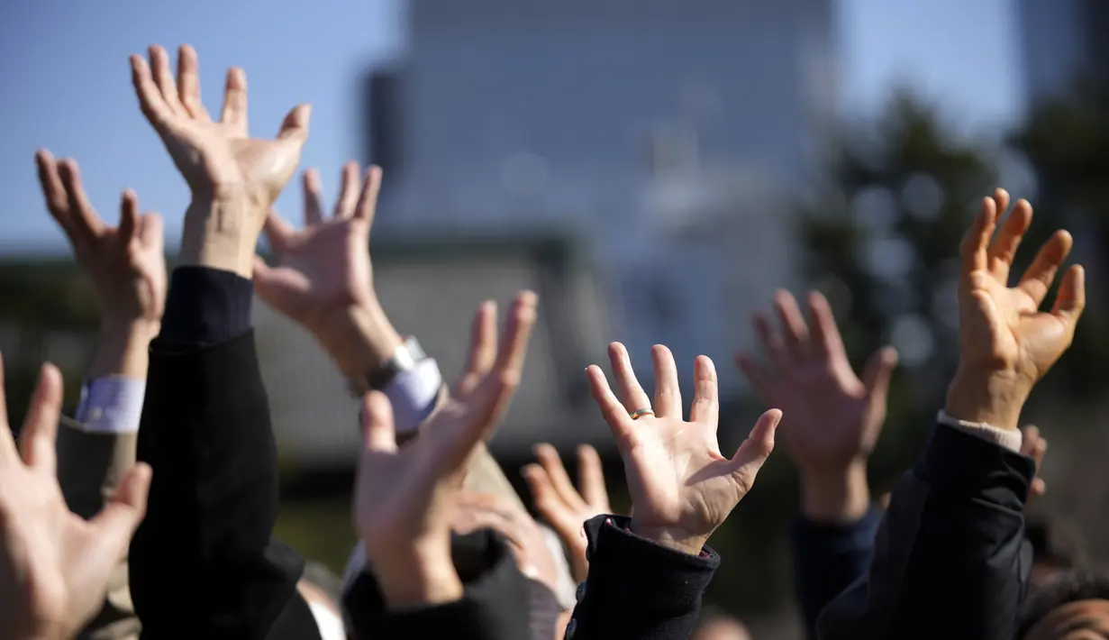 Orang-orang mencoba menangkap kacang keberuntungan yang disebarkan pada "Mame-maki," upacara pelemparan kacang di kuil Buddha Zojoji di Tokyo, 3 Februari 2022. Ritual yang diyakini membawa keberuntungan dan mengusir kejahatan dilakukan setiap tahun untuk menandai awal musim semi. (AP/Eugene Hoshiko)