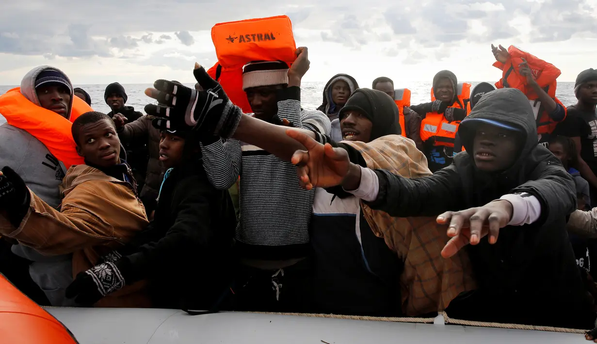 Sejumlah imigran saat meminta pertolongan penjaga pantai Spanyol LSM Proactiva Open Arms untuk keluar dari perahu karet di Laut Meditarania, sekitar 36 mil laut dari lepas pantai Libya (2/2). (Reuters/Yannis Behrakis)