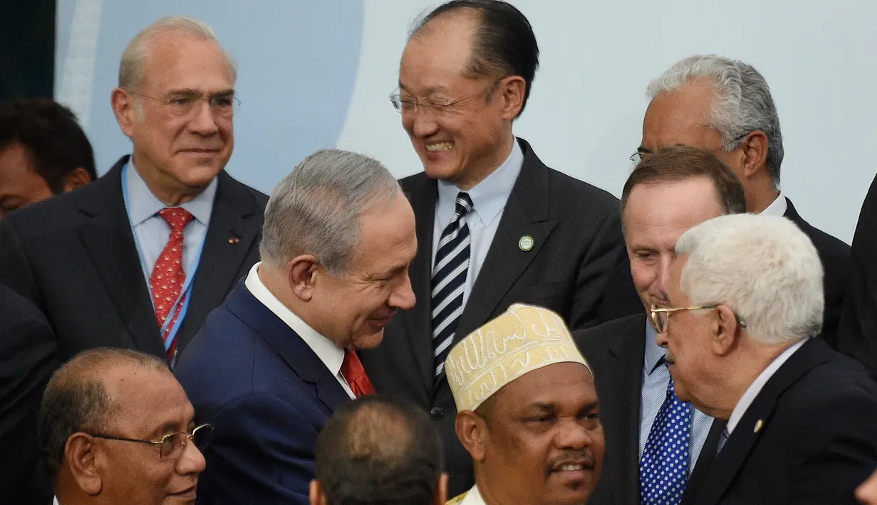 PM Israel Benjamin Netanyahu (kiri) berbincang dengan Presiden Palestina Mahmud Abbas di depan Presiden Selandia Baru disela foto bersama pada KTT Perubahan Iklim, Conference of Parties (COP) 21 di Prancis, Senin (30/11). (AFP/POOL/MARTIN BUREAU)