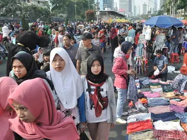 Warga melintasi lapak PKL saat car free day di MH Thamrin, Jakarta, Minggu (8/9/2019). Penutupan sebagian jalan akibat proyek revitalisasi trotoar membuat para PKL menggelar lapak hingga ke badan jalan sehingga menyebabkan aktivitas olahraga warga terhambat. (merdeka.com/Iqbal S. Nugroho)