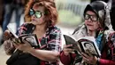Pendukung setia Basuki Tjahaja Purnama (BTP) atau Ahok, Ahokers membaca buku saat berkumpul di RTH Kalijodo, Jakarta, Kamis (24/1). Ahokers yang datang ke lokasi rata-rata mengenakan kemeja kotak-kotak. (Liputan6.com/Faizal Fanani)