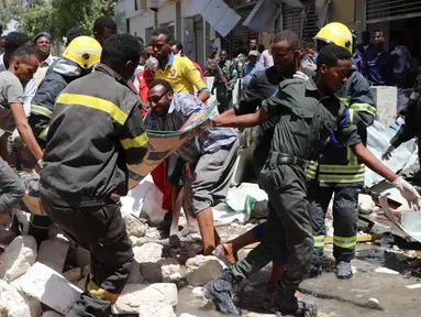Petugas membawa jenazah korban di lokasi serangan bom mobil di Distrik Hamarwayne, Mogadishu, Ibu Kota Somalia (4/2). Setidaknya sembilan orang tewas dan beberapa lainnya cedera akibat serangan bom mobil tersebut. (AFP Photo/Abdirazak Hussein Farah)