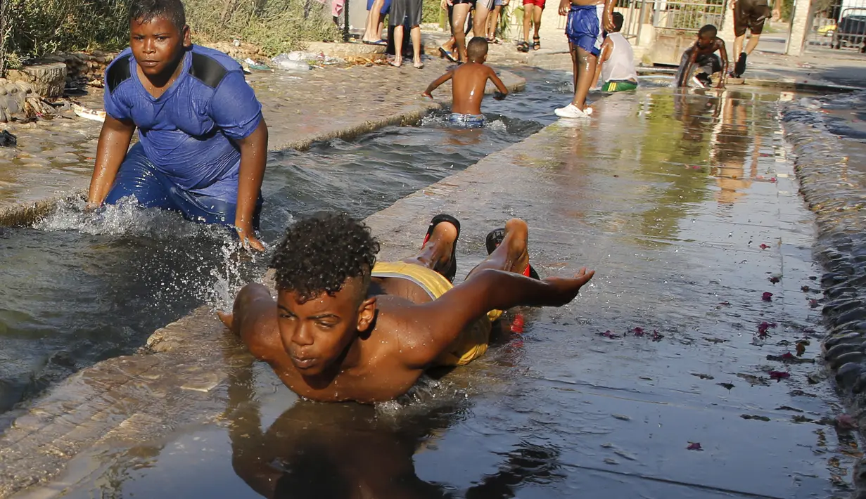 Sejumlah anak bermain air di saluran irigasi di desa Ain al-Sultan, barat laut kota Jericho, Tepi Barat (21/7/2019). Saat ini  kota Jerikho memiliki populasi sebesar 25.000 orang Palestina dan Israel. (AFP Photo/Jaafar Ashtiyeh)