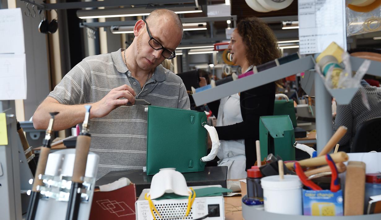 Pengrajin merapikan bagian tas saat bekerja di bengkel produsen barang-barang mewah Hermes di Allenjoie, Perancis, Kamis (5/4). Hermes merupakan tas berbahan kulit yang biasanya diproduksi secara limited edition. (SEBASTIEN BOZON/AFP)