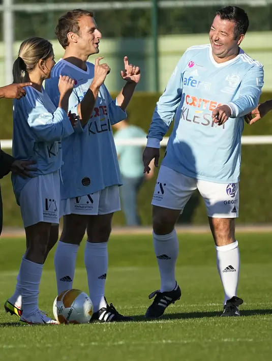 Presiden Prancis Emmanuel Macron (tengah) berbicara dengan rekan satu timnya sebelum bermain pada laga amal peringatan 50 tahun Varietes Club di Stadion Leo Lagrange, Poissy, Prancis, Kamis (14/10/2021). Macron bermain laga amal untuk Yayasan Rumah Sakit. (AP Photo/Michel Euler)