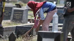 Seorang anak membersihkan salah satu makam di TPU Penggilingan, Pulogadung, Jakarta, Kamis (10/5). Tradisi ziarah jelang Ramadan menjadi berkah bagi anak-anak pembersih makam atau biasa dikenal 'Ngoret'. (Merdeka.com/Iqbal S. Nugroho)