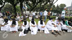 Sejumlah demonstran perempuan beristirahat di pinggir taman Jalan Medan Merdeka Selatan, Jumat (4/11). Ratusan ribu massa aksi damai melakukan aksi menuntut penegakan hukum kasus dugaan penistaan agama. (Liputan6.com/Yoppy Renato)