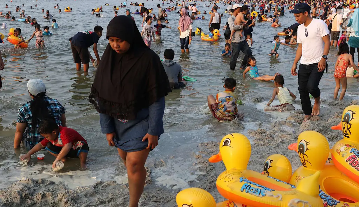 Seorang ibu berjalan di dekat pelampung berbentuk bebek di Pantai Karnaval Ancol, Jakarta, Sabtu (16/6). H+1 libur Lebaran, jumlah pengunjung di Ancol mencapai 88.143 orang. (Liputan6.com/Immanuel Antonius)