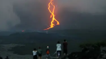 Warga melihat guguran lava pijar yang keluar dari gunung api Piton de la Fournaise atau Peak of the Furnace di Pulau Reunion, Samudera Hindia, Prancis, Selasa (13/8/2019). Letusan Piton de la Fournaise berlanjut hingga hari ketiga. (Richard BOUHET/AFP)