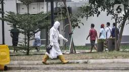 Tenaga kesehatan melintas dekat pasien COVID-19 yang berolahraga di sekitar taman Rumah Sakit Darurat (RSD) Wisma Atlet, Kemayoran, Jakarta, Minggu (6/12/2020). Setiap pagi dan sore hari pihak RSD Wisma Atlet memperbolehkan pasien Covid-19 keluar kamar untuk berolahraga. (merdeka.com/Iqbal Nugroho)