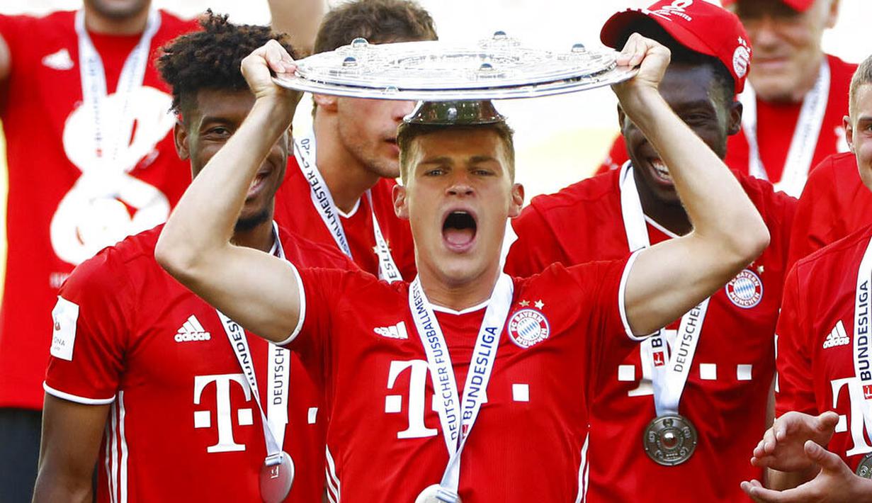 Pemain Bayern Munchen, Joshua Kimmich, mengangkat trofi juara Bundesliga usai melawan Wolfsburg di Volkswagen Arena, Sabtu (27/6/2020). Kemenangan itu membuat Bayern kokoh di puncak klasemen sekaligus mengunci gelar juara Bundesliga. (AP/Kai Pfaffenbach)