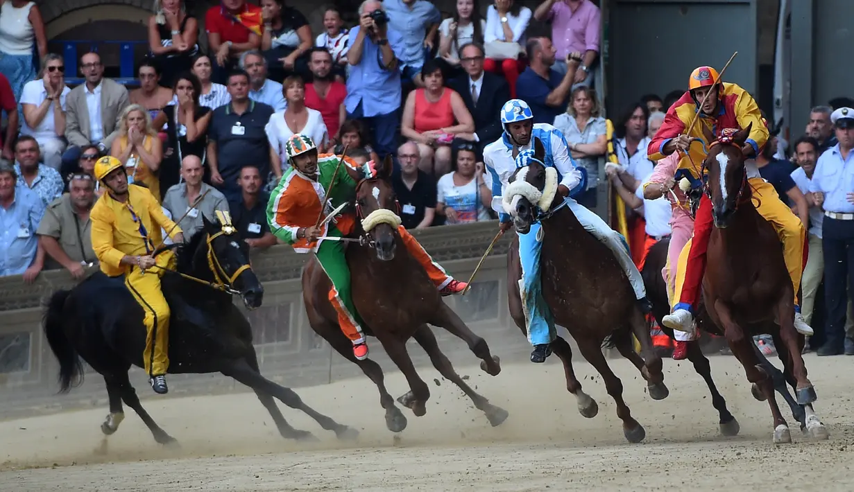 Para joki memacu kudanya saling balap saat mengikuti balapan kuda Italia historis Palio di Siena, Italia (16/8). Hari-hari menjelang diadakannya Palio, seluruh kota dipenuhi dengan suasana abad lampau. (AFP Photo/Filippo Monteforte)