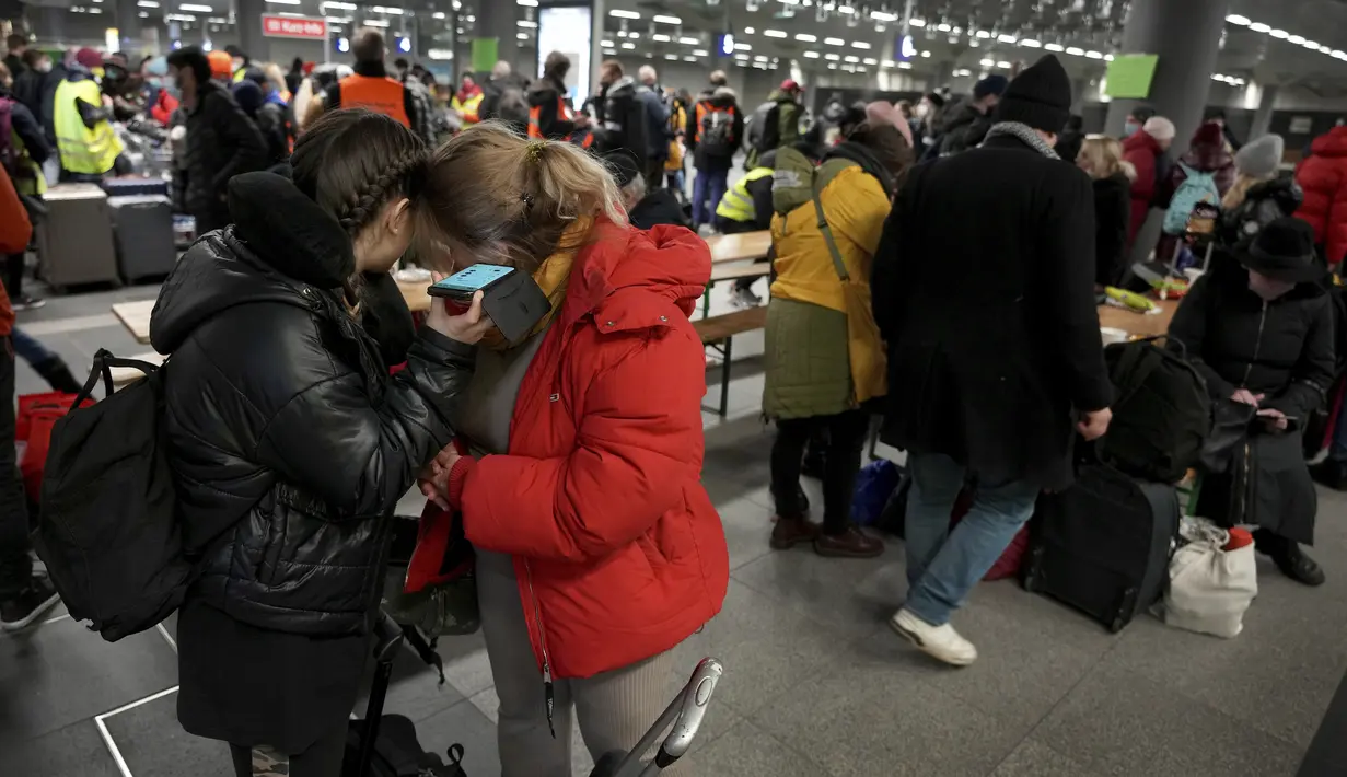 Dua orang memegang perangkat seluler setelah kedatangan kereta dengan pengungsi Ukraina di stasiun utama di Berlin, Jerman, Selasa  (1/3/2022). Menjelang malam, diperkirakan 300 orang tiba di Berlin dengan kereta api. Sejumlah relawan kemudian merawat orang-orang yang terdampar. (AP Photo/Michael So