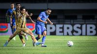 Pemain Persib Bandung, Ezra Walian (kanan) melepaskan tendangan yang berusaha diblok pemain Dewa United, Rangga Muslim pada laga pekan ke-3 BRI Liga 1 2023/2024 di Stadion Gelora Bandung Lautan Api (GBLA), Bandung, Jumat (14/07/2023). (Bola.com/Bagaskara Lazuardi)