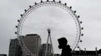 Seorang pria memakai masker saat melewati London Eye di London, Kamis (29/10/2020). Sekitar 100.000 orang terjangkit virus corona setiap hari di Inggris, menurut studi terbaru Imperial College London. (AP Photo/Frank Augstein)