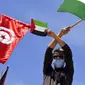 Warga Tunisia mengibarkan bendera Tunisia dan bendera Palestina saat protes untuk mendukung warga Palestina di Jalur Gaza di Tunis, Tunisia, Sabtu (15/5/2021). Serangan udara Israel menghancurkan gedung bertingkat tinggi di Kota Gaza yang menjadi kantor AP dan media lainnya. (AP Photo/Hassene Dridi)