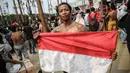 Seorang warga menunjukkan bendera merah putih saat mengikuti lomba panjat pinang Kolosal dalam rangka merayakan HUT ke 72 RI di Pantai Karnaval Ancol, Jakarta, Kamis (17/8). (Liputan6.com/Faizal Fanani)