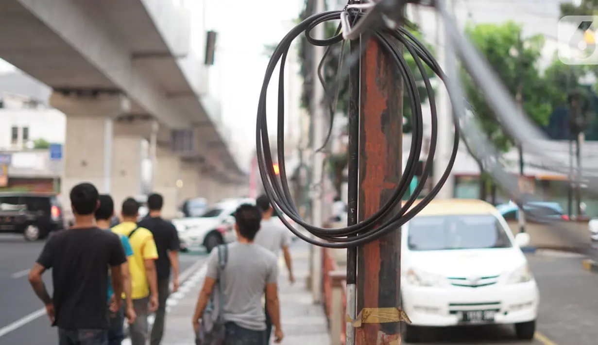 Instalasi kabel menjuntai di Jalan Panglima Polim, Kebayoran Baru, Jakarta, Kamis (31/10/2019). Buruknya pemasangan instalasi kabel di Ibukota menyebabkan banyak kabel yang menjuntai hingga mengganggu ketertiban umum. (Liputan6.com/Immanuel Antonius)