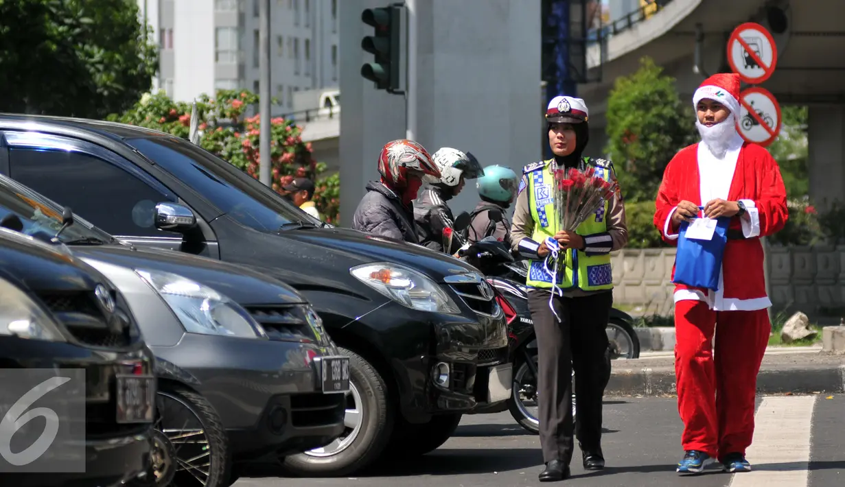 Menyambut Hari Natal 2015, anggota Kepolisian Polres Jakarta Barat kenakan topi Sinterklas dan bagikan bunga serta masker kepada pengguna jalan di kawasan Tomang, Jakarta, Rabu (23/12). (Liputan6.com/Yoppy Renato)