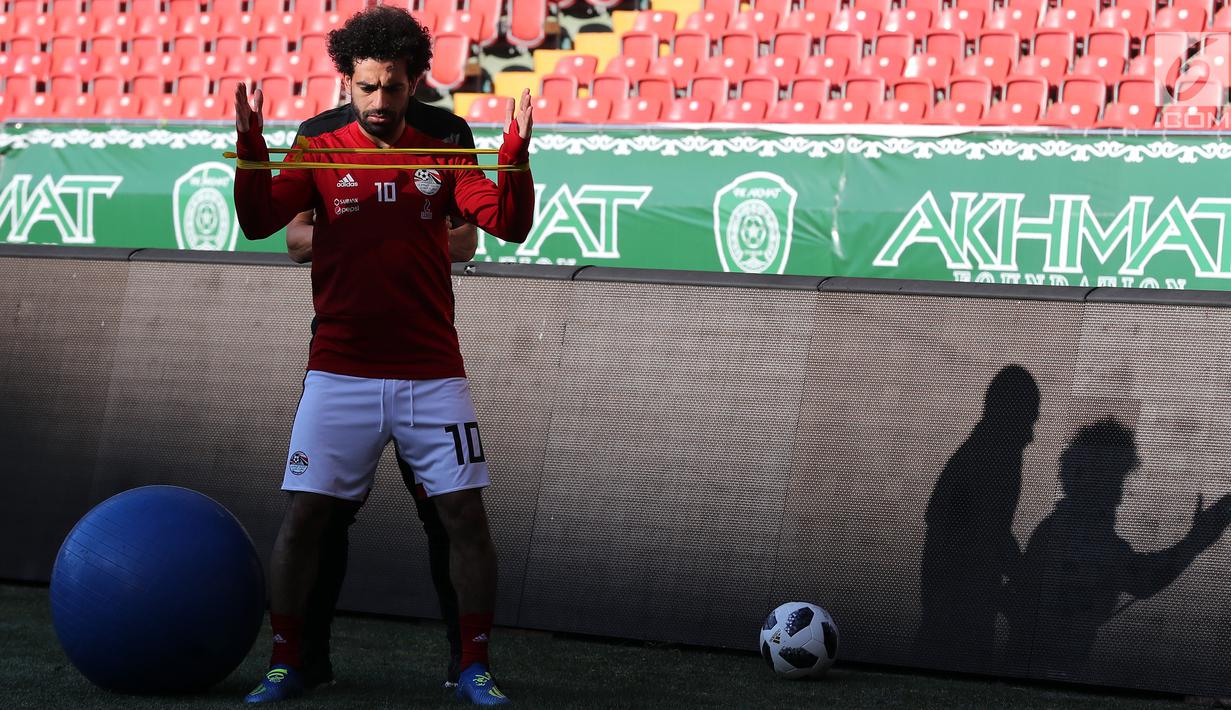 Pemain timnas Mesir Mohamed Salah bersama tim kesehatan melatih bahunya selama sesi pelatihan di stadion Akhmat Arena di Grozny (12/6). Meski masih dibekap cedera bahu, Salah tetap optimis dapat tampil di Piala Dunia 2018 Rusia. (AFP Photo/Karim Jaafar)
