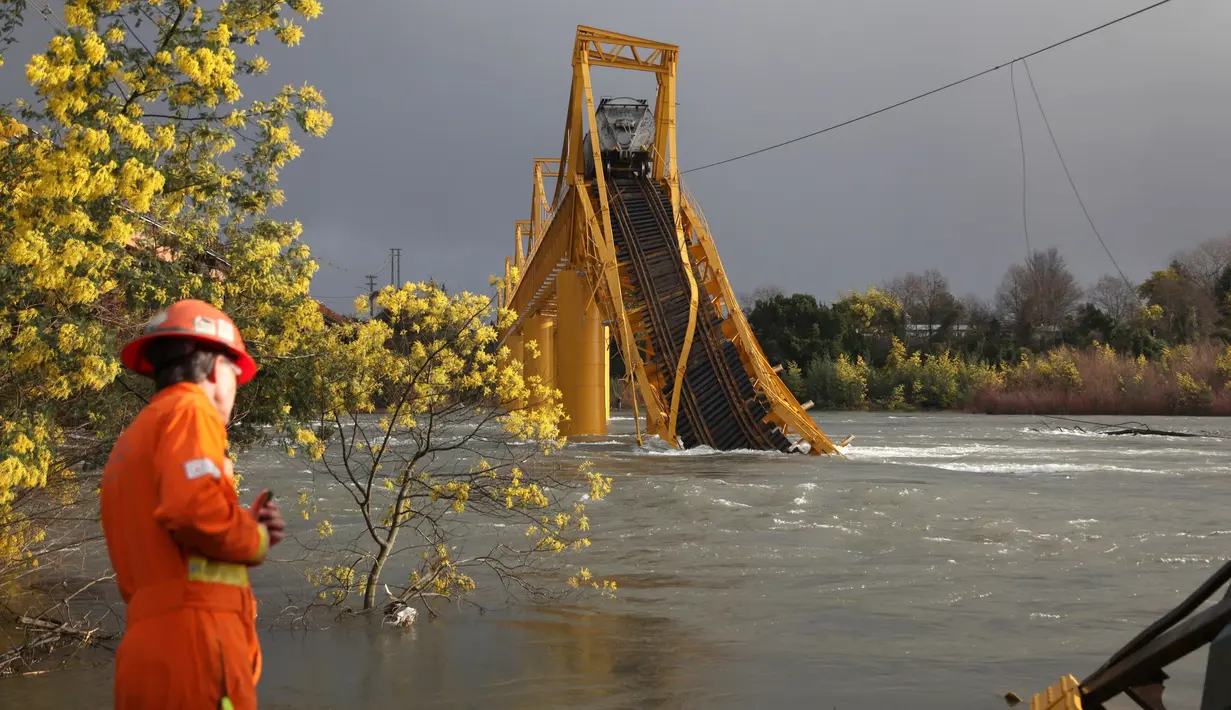 Petugas evakuasi melihat kereta barang yang anjlok ke dalam Sungai Tolten setelah jembatan tersebut runtuh di Desa Pitrufquen, sabelah selatan Chili. (18/08). (REUTERS/Cristobal)