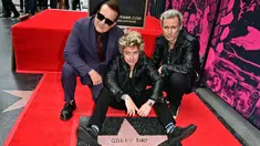 Personel grup band punk rock Green Day, Billie Joe Armstrong (tengah), Mike Dirnt (kanan), dan Tre Cool berpose dengan bintang mereka yang baru saja diresmikan di Hollywood Walk of Fame dalam sebuah upacara di Hollywood, California, Amerika Serikat pada 1 Mei 2025. (Frederic J. Brown/AFP)