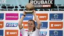 Pembalap Team SD Worx - Protime, Lotte Kopecky mengangkat trofi setelah memenangkan perlombaan balap sepeda Paris Roubaix Femmes 2024 yang menempuh 148,5km antara Denain hingga Roubaix, Prancis, Sabtu (06/07/2024) waktu setempat. (AFP/Christophe Ena)