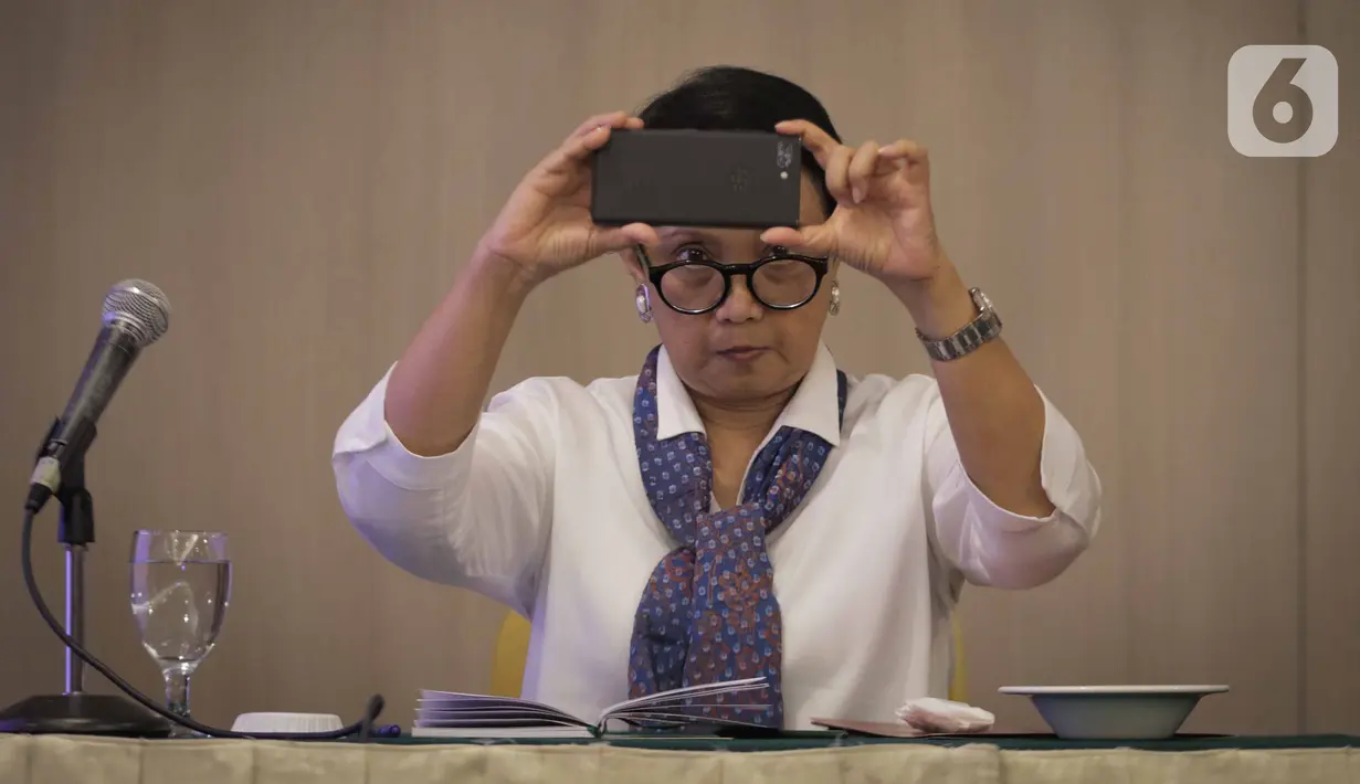 Menteri Luar Negeri Retno LP Marsudi mengambil gambar dengan ponselnya saat menghadiri acara forum pimred di Jakarta, Selasa (3/3/2020). Acara tersebut membahas mengenai permasalahan aktual yang terjadi di Indonesia salah satunya terkait virus corona (COVID-19) . (Liputan6.com/Faizal Fanani)