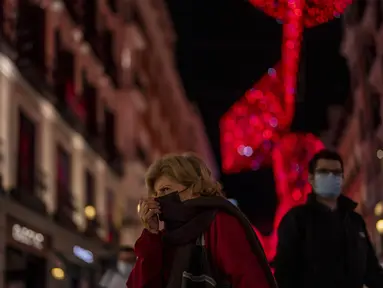 Orang-orang yang memakai masker berjalan di pusat kota Madrid, Rabu (22/12/2021). Perdana Menteri Spanyol Pedro Sanchez mengadakan rapat Kabinet khusus untuk mengesahkan undang-undang yang mewajibkan penggunaan masker di luar ruangan di tengah lonjakan rekor kasus COVID-19. (AP Photo/Manu Fernandez)
