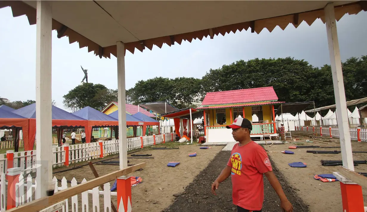Pekerja melintasi rumah adat betawi jelang pelaksanaan Festival Lebaran Betawi IX di Lapangan Banteng, Jakarta, Kamis (11/8). Festival ini diharapkan dapat menjadi salah satu destinasi wisata di Ibukota. (Liputan6.com/Immanuel Antonius)