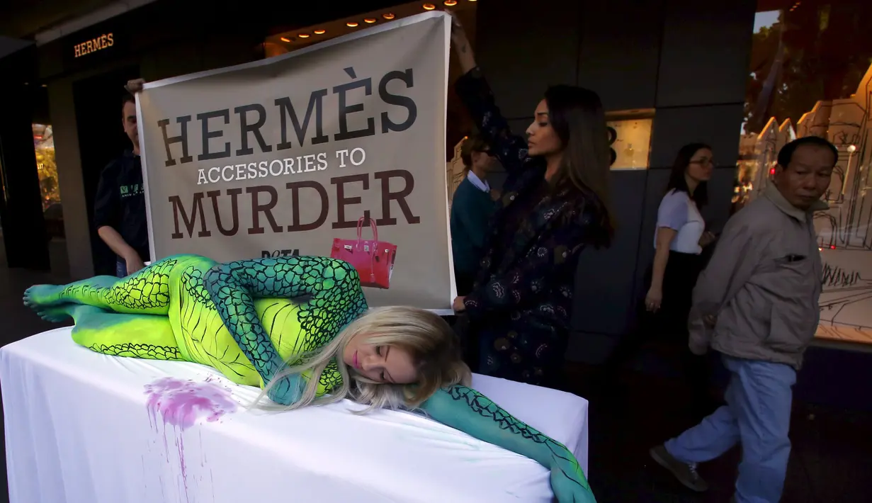 Model Australia Rochelle Relf memenuhi tubuhnya dengan lukisan mirip kulit buaya didepan toko Hermes, Sydney, Australia, Selasa (11/8/2015). Aksi ini sebagai bentuk protes atas penggunaan kulit buaya sebagai produk fashion. (REUTERS/David Gray)