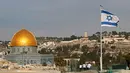 Bendera Israel berkibar di atap sbangunan di Kota Tua Yerusalem di seberang Dome of the Rock di kompleks masjid Al-Aqsa, (5/12). Menurut pejabat AS, Presiden AS Donald Trump akan mengakui Yerusalem sebagai ibu kota Israel. (AFP Photo/Thomas Coex)