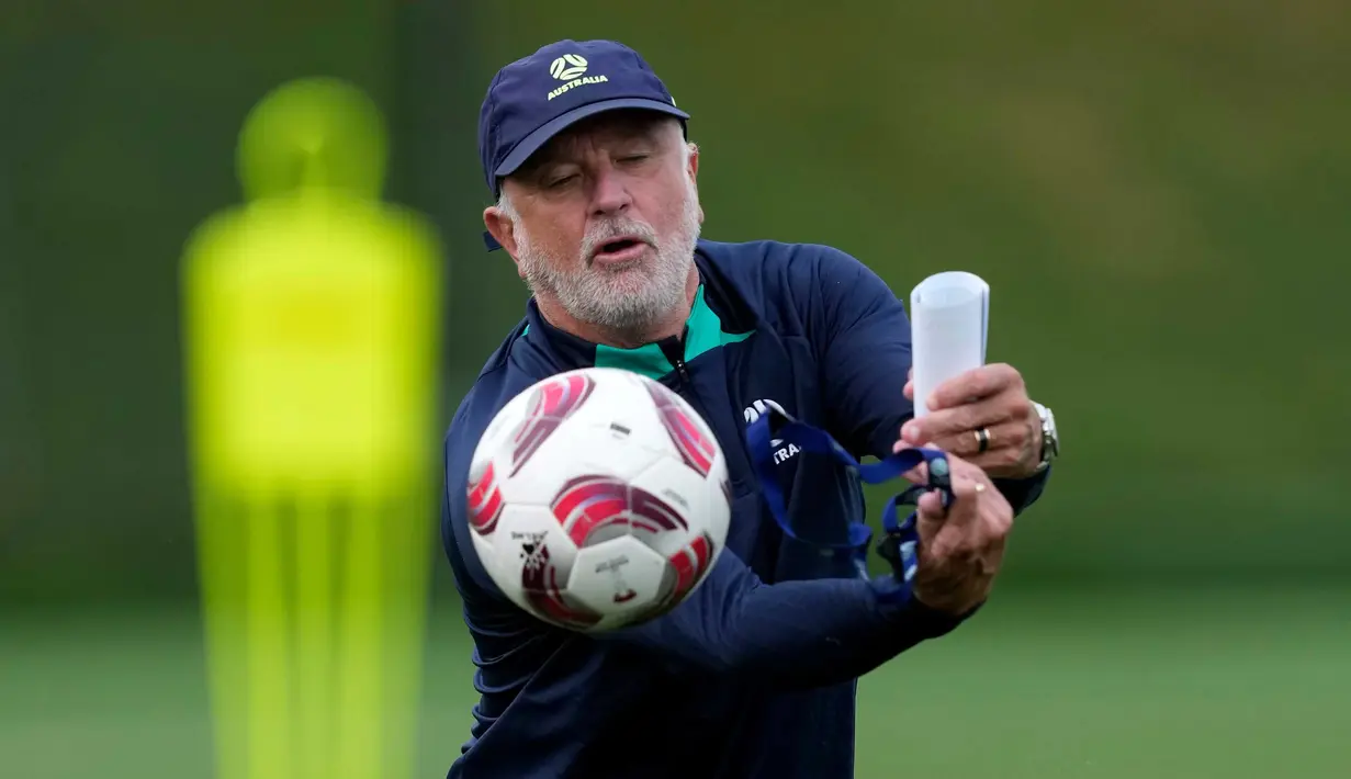 Pelatih kepala Australia Graham Arnold menghentikan bola saat sesi latihan tim nasional, di Doha, Qatar, Sabtu, 27 Januari 2024. (AP Photo/Thanassis Stavrakis)