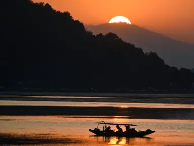 Nelayan menunggu di perahu kecil setelah memancing di Danau Dal saat matahari terbenam di Srinagar (9/9/2019). Danau Dal dijuluki sebagai Jewel in the Crown of Kashmir atau Srinagar Jewel. (AFP Photo/Tauseef Mustafa)