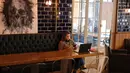 Seorang perempuan duduk dengan laptopnya di sebuah kafe di Beirut pada 14 Januari 2022. Kafe-kafe Beirut sekarang berfungsi sebagai tempat kerja pengganti bagi orang-orang yang bergulat dengan kekurangan listrik dan pemutusan internet yang berasal dari krisis ekonomi. (JOSEPH EID / AFP)