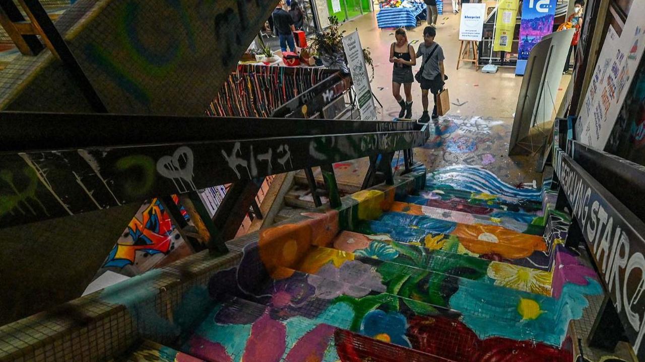 Pengunjung berjalan di dekat anak tangga penuh warna di Peace Centre, sebuah mal terbengkalai yang berubah menjadi kawasan seni tak terduga, di Singapura, pada 19 Januari 2024. Grafiti merupakan hal yang terlarang di Singapura. Para pelakunya terancam men