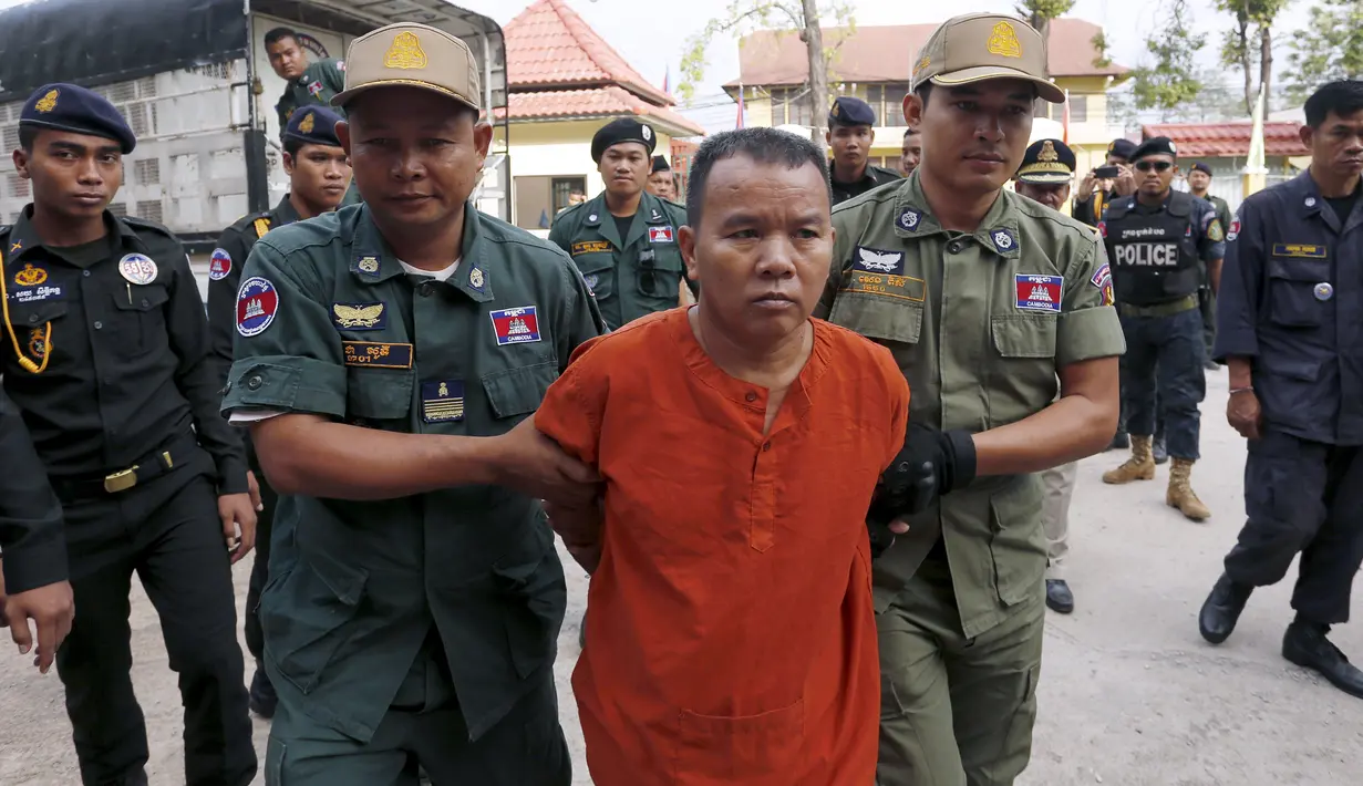 Yem Chrin (tengah) dikawal oleh petugas polisi saat tiba di Pengadilan Provinsi Battambang,Kamboja,Kamis (3/12). Pengadilan Kamboja menghukum Yem Chrin  25 tahun penjara dengan kasus pembunuhan dan penyebaran HIV lebih dari 270 orang. (REUTERS/Stringer)