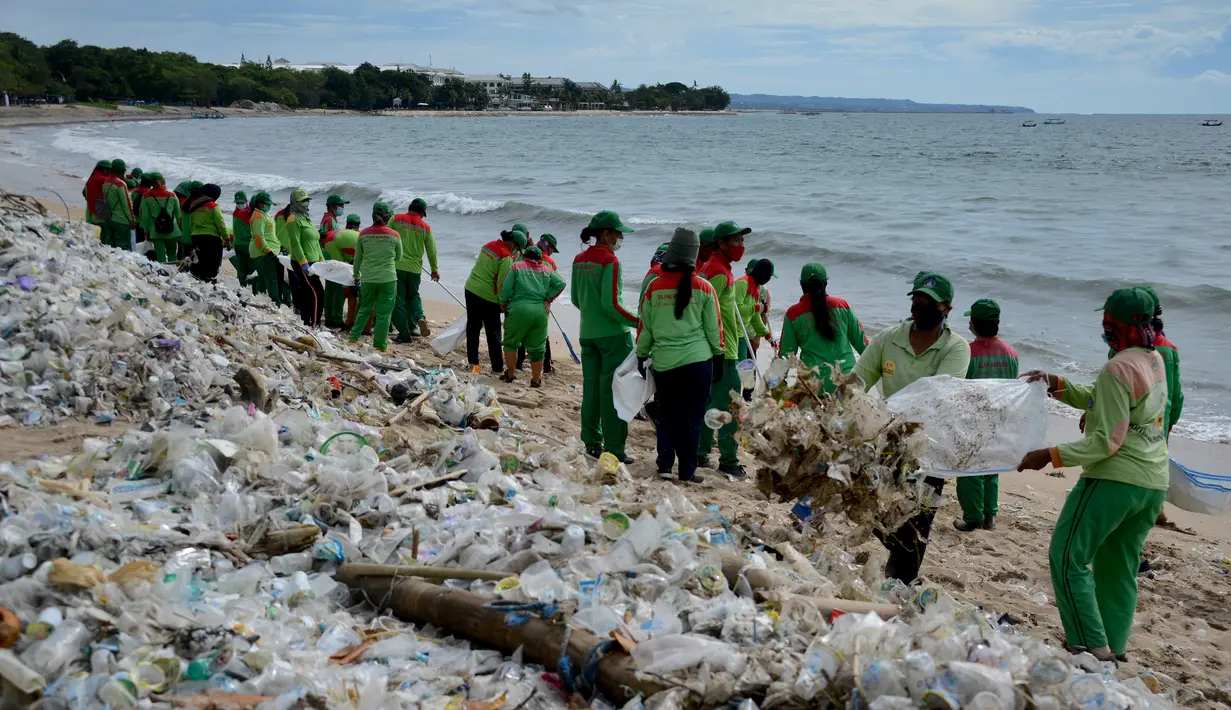 Pekerja mengumpulkan sampah plastik saat membersihkan pantai Kuta dekat Denpasar di pulau wisata Bali (6/1/2021). Sampah kemudian dimasukkan ke dalam truk untuk dibawa ke tempat pembuangan sampah. (AFP/Sonny Tumbelaka)