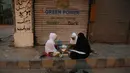 Sebuah keluarga berbuka puasa di trotoar setelah menerima makanan gratis selama pandemi Covid-19 di Karachi, Pakistan, Minggu, (10/5/2020). (AP/Fareed Khan)