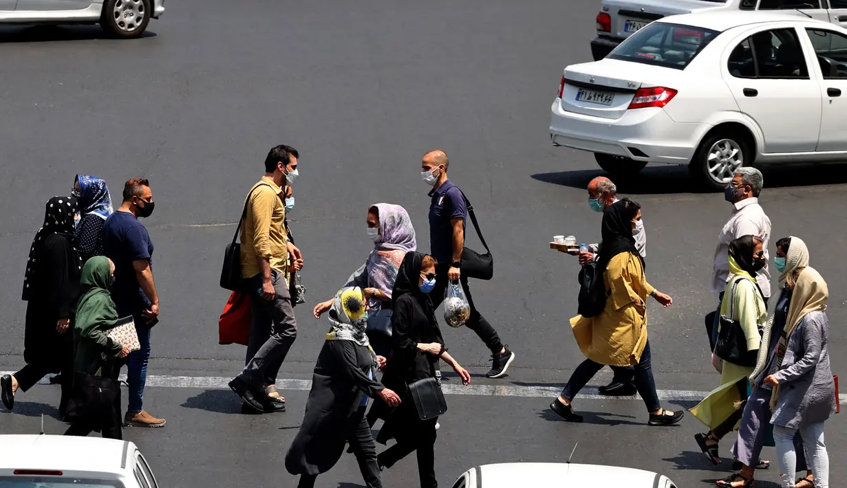 Warga Iran yang mengenakan masker menyeberang jalan di ibu kota Teheran, Sabtu (3/7/2021). Presiden Hassan Rouhani mengaku khawatir Iran akan dilanda gelombang kelima pandemi Covid-19 karena kemunculan virus corona varian Delta. (ATTA KENARE/AFP)