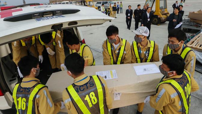 Petugas memasukkan peti mati berisi jenazah yang ditemukan tewas dalam truk kontainer di Inggris ke dalam ambulans setibanya di bandara internasional Noi Bai, Hanoi, Rabu (27/11/2019). Sebanyak 16 dari 39 jenazah telah tiba di Vietnam untuk dibawa ke kampung halaman masing-masing. (Nhac NGUYEN/AFP)