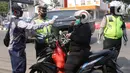 Petugas memeriksa suhu tubuh pengendara saat pelaksanaan Pembatasan Sosial Berskala Besar (PSBB) di kawasan Gading Serpong, Tangerang Selatan, Sabtu (18/4/2020). Pengukuran suhu tubuh tersebut merupakan cek point dari PSBB yang baru saja diberlakukan di Tangerang Raya. (Liputan6.com/Angga Yuniar)