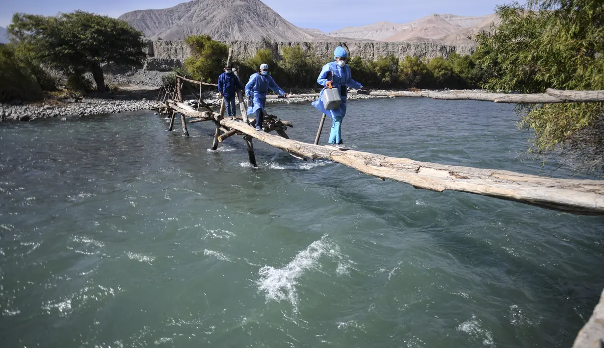 Petugas kesehatan menyeberangi Sungai Camana untuk vaksinasi Covid-19 kepada warga lanjut usia di desa pedalaman di Arequipa, Peru (2/7/2021). Peru menggencarkan vaksinasi warga lanjut usia dengan vaksin Pfizer-BioNTech sebagai upaya untuk mengatasi pencegahan pandemi Covid-19. (AFP/Diego Ramos)