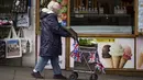 Seorang perempuan mendorong troli berhiaskan bendera Union Jack di Windsor, Jumat, 5 Mei 2023. Penobatan Raja Charles III akan berlangsung di Westminster Abbey pada 6 Mei. (AP Photo/Andreea Alexandru)