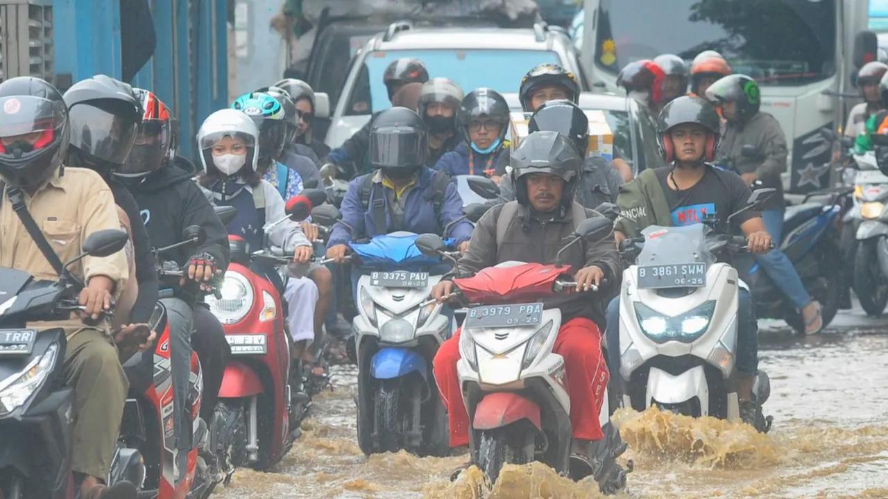 Pengendara menerobos banjir yang mengenangi Jalan Raya Bogor di depan Pasar Induk Kramat Jati, Jakarta, Kamis (30/11/2023). <br>