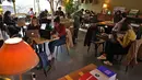 Orang-orang Lebanon duduk dengan laptop mereka di sebuah kafe di Beirut pada 14 Januari 2022.	Kafe-kafe Beirut sekarang berfungsi sebagai tempat kerja pengganti bagi orang-orang yang bergulat dengan kekurangan listrik dan pemutusan internet yang berasal dari krisis ekonomi. (JOSEPH EID / AFP)