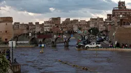 Sejumlah warga melihat jalanan yang terendam banjir di Sanaa, Yaman, Selasa (2/8). Hujan lebat yang mengguyur Sanaa membuat salah satu ruas jalan di kota itu berubah seakan menjadi sungai. (REUTERS / Khaled Abdullah)